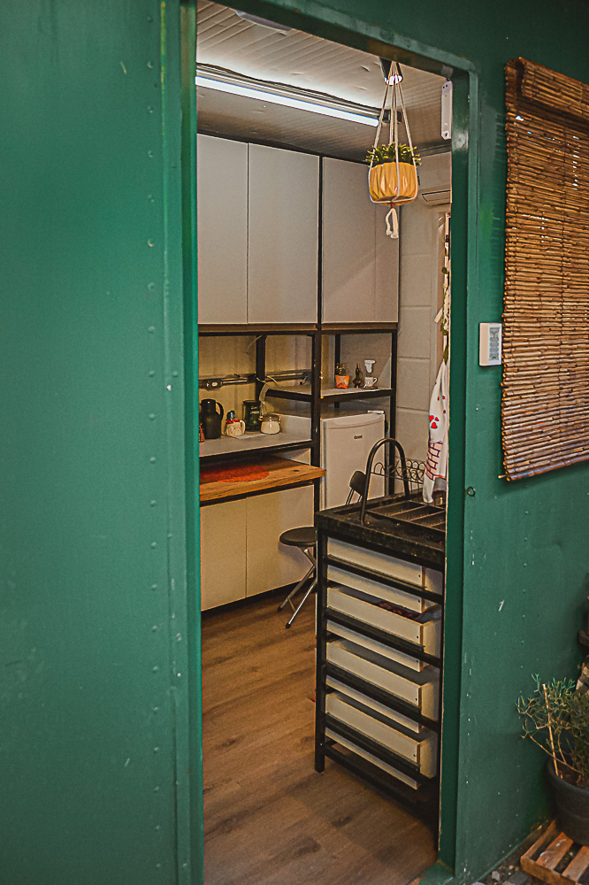 Porta verde do container abrindo para a cozinha aconchegante do Loft Ninho